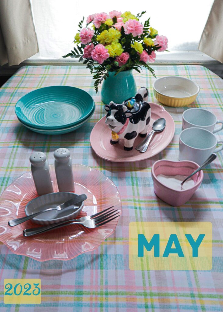 Ladies tea table with mugs sugar cow shaped creamer aqua salad bowls on a pastel plaid tablecloth