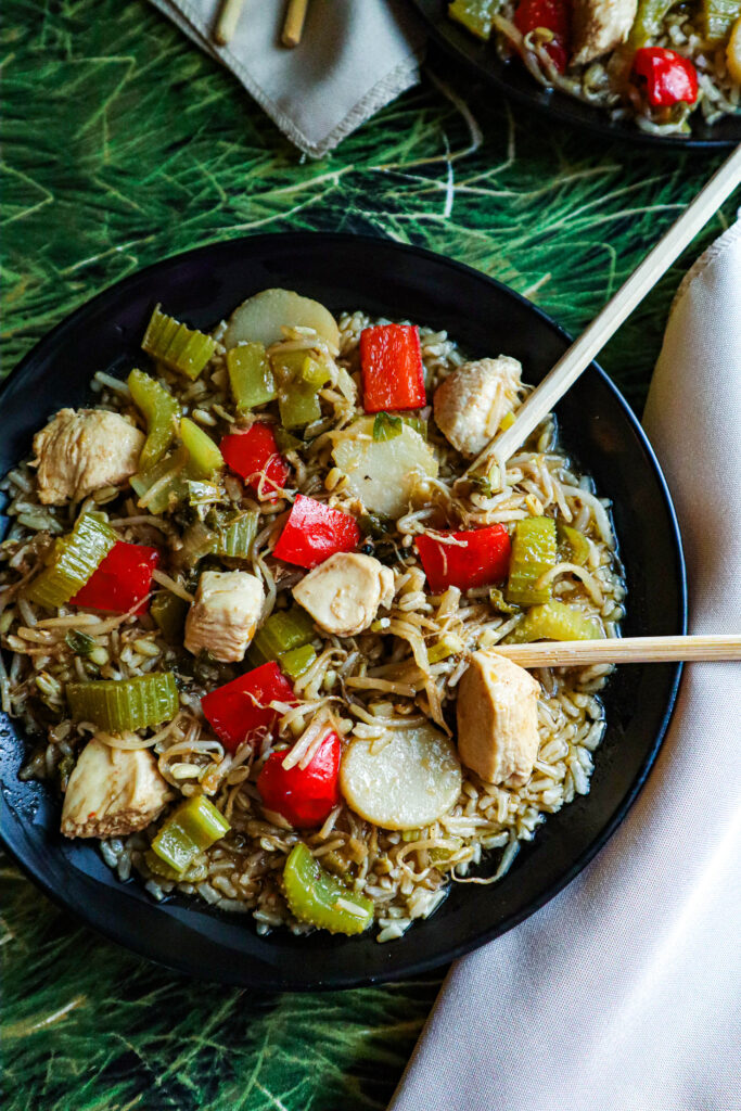 chicken stir fry with red pepper celery chicken water chestnuts served in a black dish with chop sticks