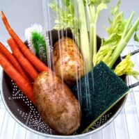 vegetables being washed in the kitchen sink