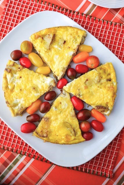 4 slices of potato and onion frittata with multi colored grape tomatoes between slices