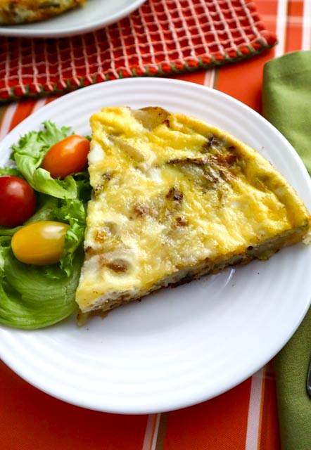 one slice of potato and onion frittata with lettuce and grape tomatoes on the side