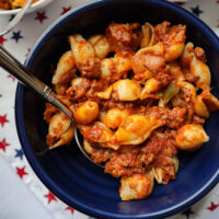 american chop suey with pasta shells served from blue bowl red white and blue stars cloth under bowl