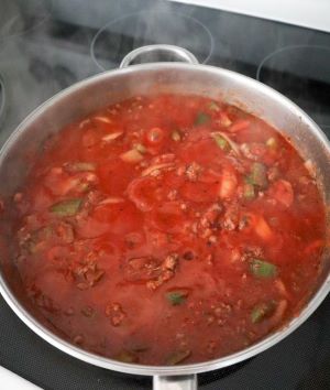 crushed tomato added to vegetables in skillet