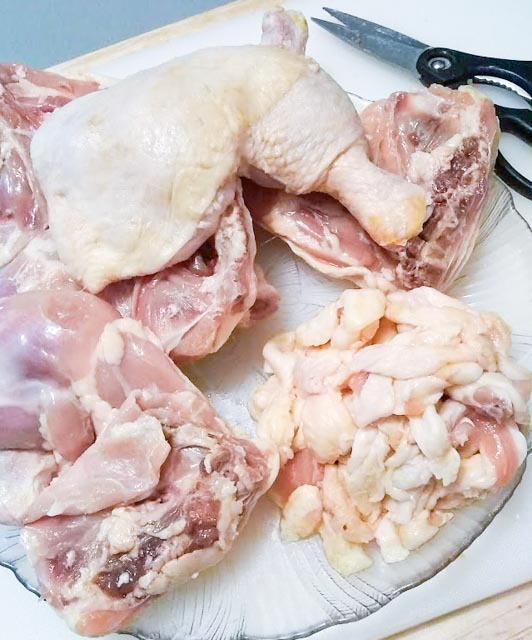 trimmed chicken legs and a pile of fat that has been cut off