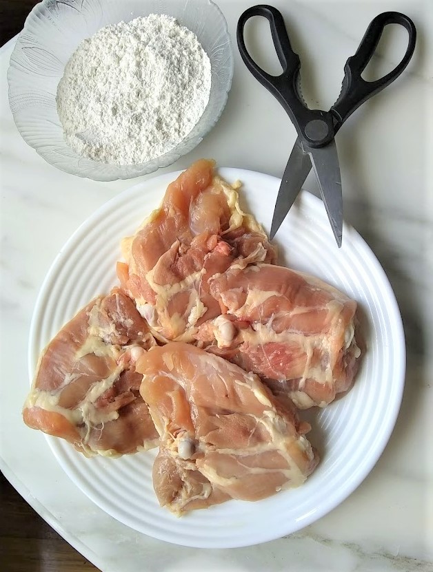 trimming the fat from chicken thighs before dredging