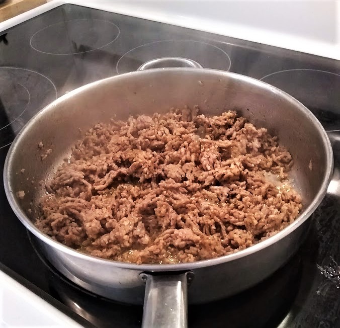 italian sausage meat cooking in skillet with steam