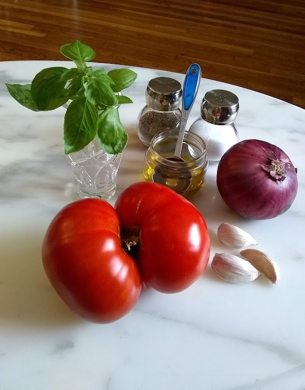 tomato salad ingredients tomato onion garlic basil olive oil salt and pepper on marble table