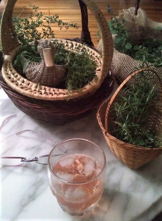 herbs sorted in baskets on table with eyeglasses and a glass of wine