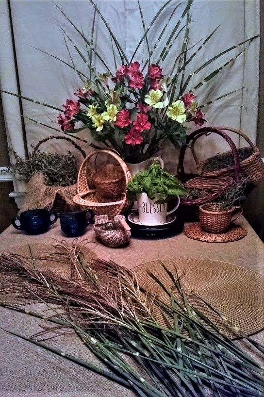 night shot of table with fall flower arrangement baskets of herbs and ornamental grass