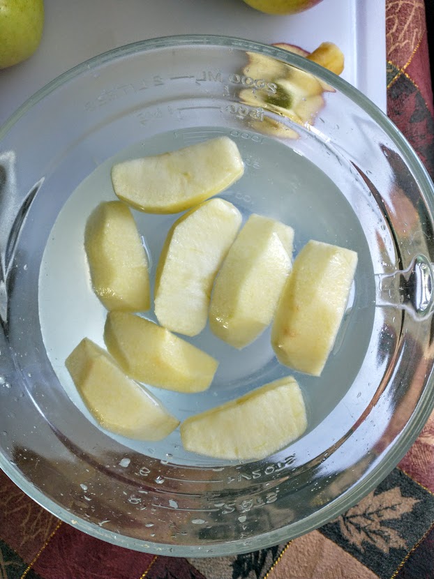 a bowl of apple slices in lemon water to keep them from browning