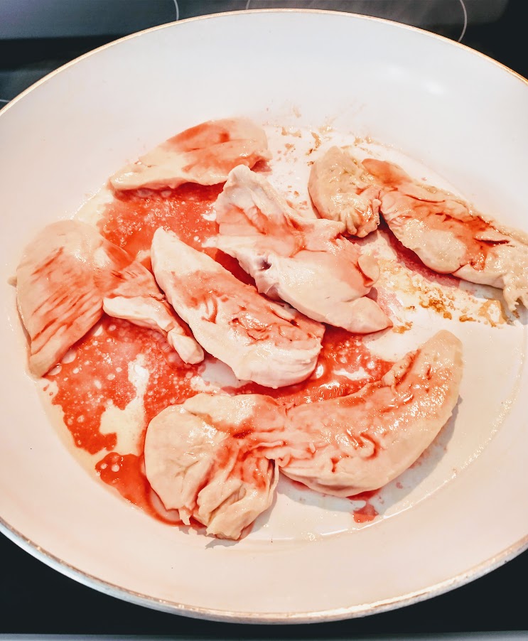 chicken tenders in a skillet with melted butter and some red cherry juice