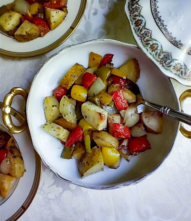 roasted summer vegetables green and yellow peppers plum tomatoes potatoes onion served in a gold and ivory serving dish