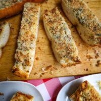 3 slices of cut garlic bread on a wooden cutting board