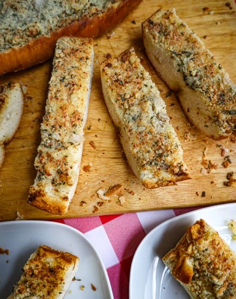 3 slices of cut garlic bread on a wooden cutting board