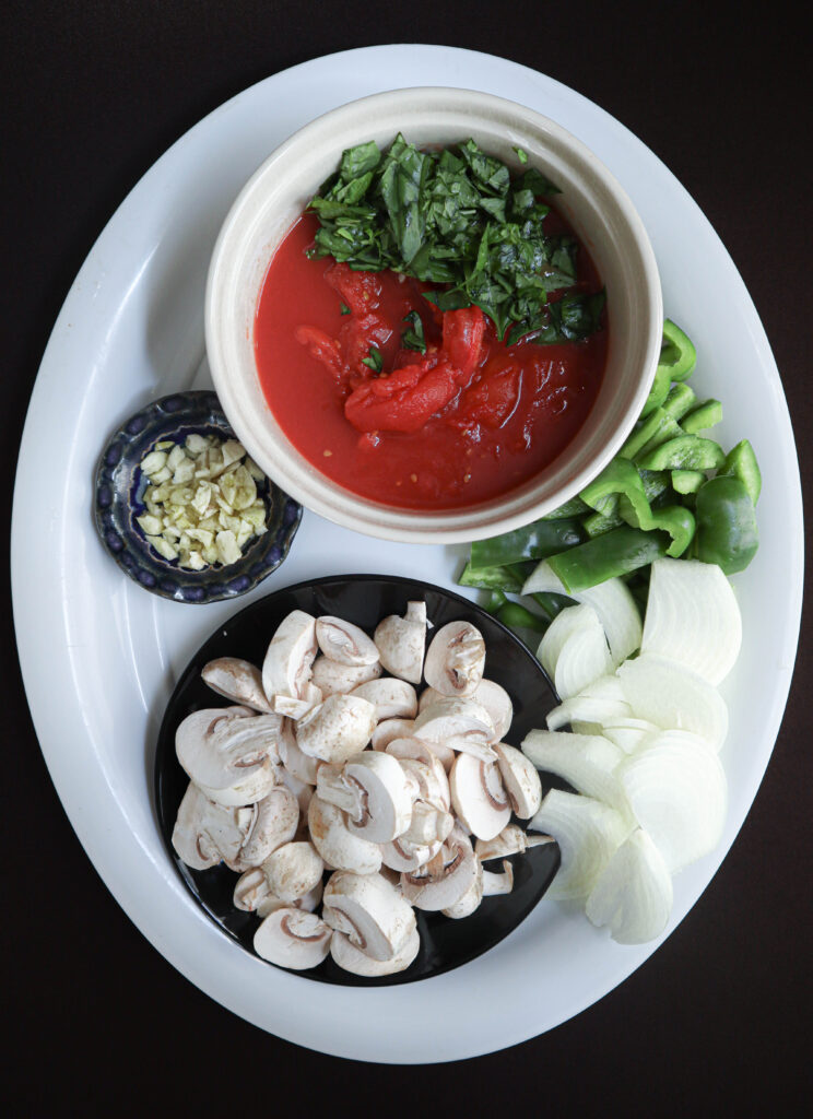 vegetables chopped for chicken cacciatore with pasta canned peeled plum tomatoes cut basil leaves chopped garlic sliced green pepper onion and mushrooms