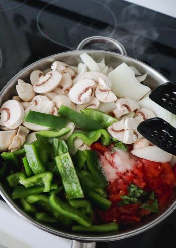 Tomatoes, green pepper, onion mushrooms garlic, basil and salt, have been added to the skillet over the chicken.