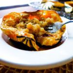 one half of a colorful fall squash baked with butter brown sugar and maple syrup served in a shallow bowl