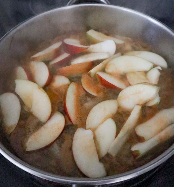 sliced apples and cider sauce added to skillet with sauteed onions