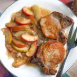 pork chops apples and onions in a sweet and savory cider sauce served on a platter