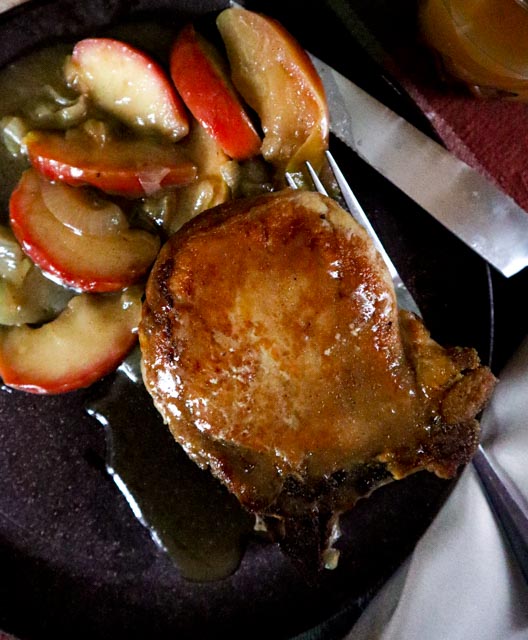 center cut pork chop with an apple and onion side dish all dripping with a homemade apple cider sauce