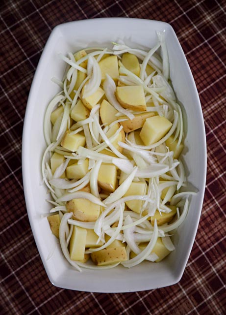 chopped potatoes and sliced onions in a casserole dish