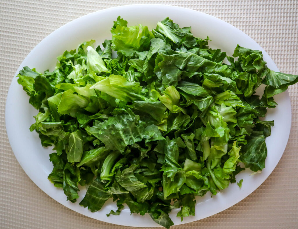 a head of escarole lettuce chopped on a white platter