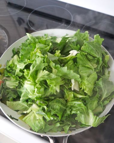 escarole leaves steaming in skillet