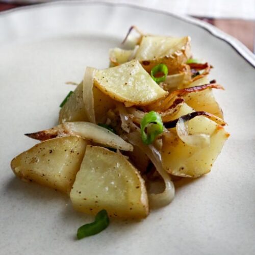 potato and onion casserole with chopped scallions as a garnish