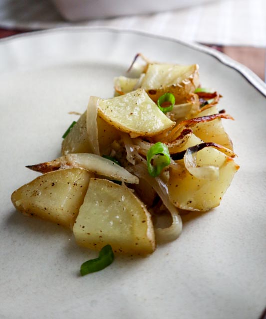 potato and onion casserole with chopped scallions as a garnish