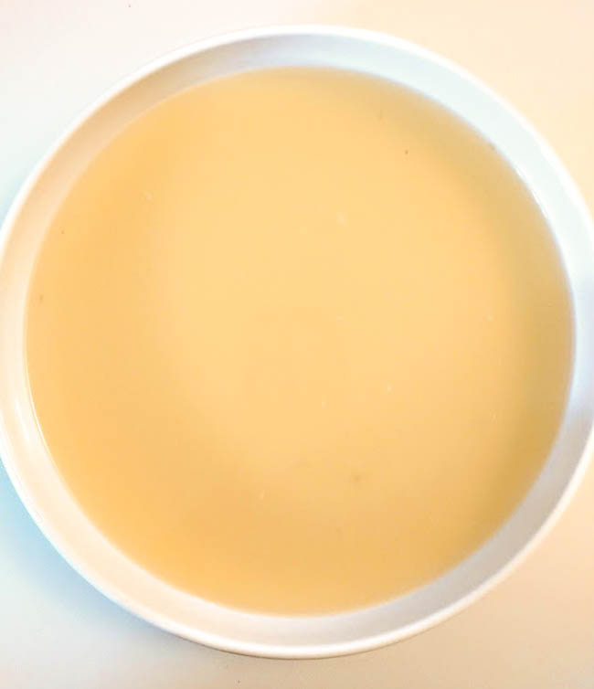 a bowl of clear turkey stock in a white bowl