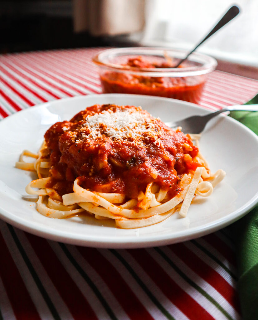 marinara sauce over pasta in white serving dish with grated cheese on top