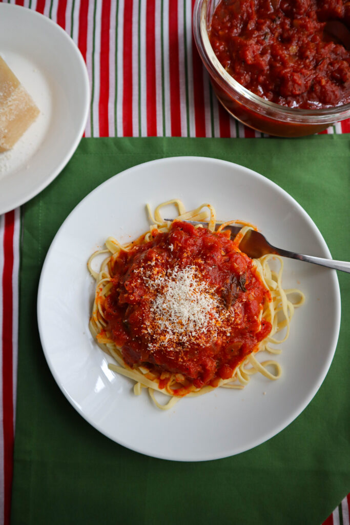 a plate of pasta with a heap of marinara sauce and grated cheese on top