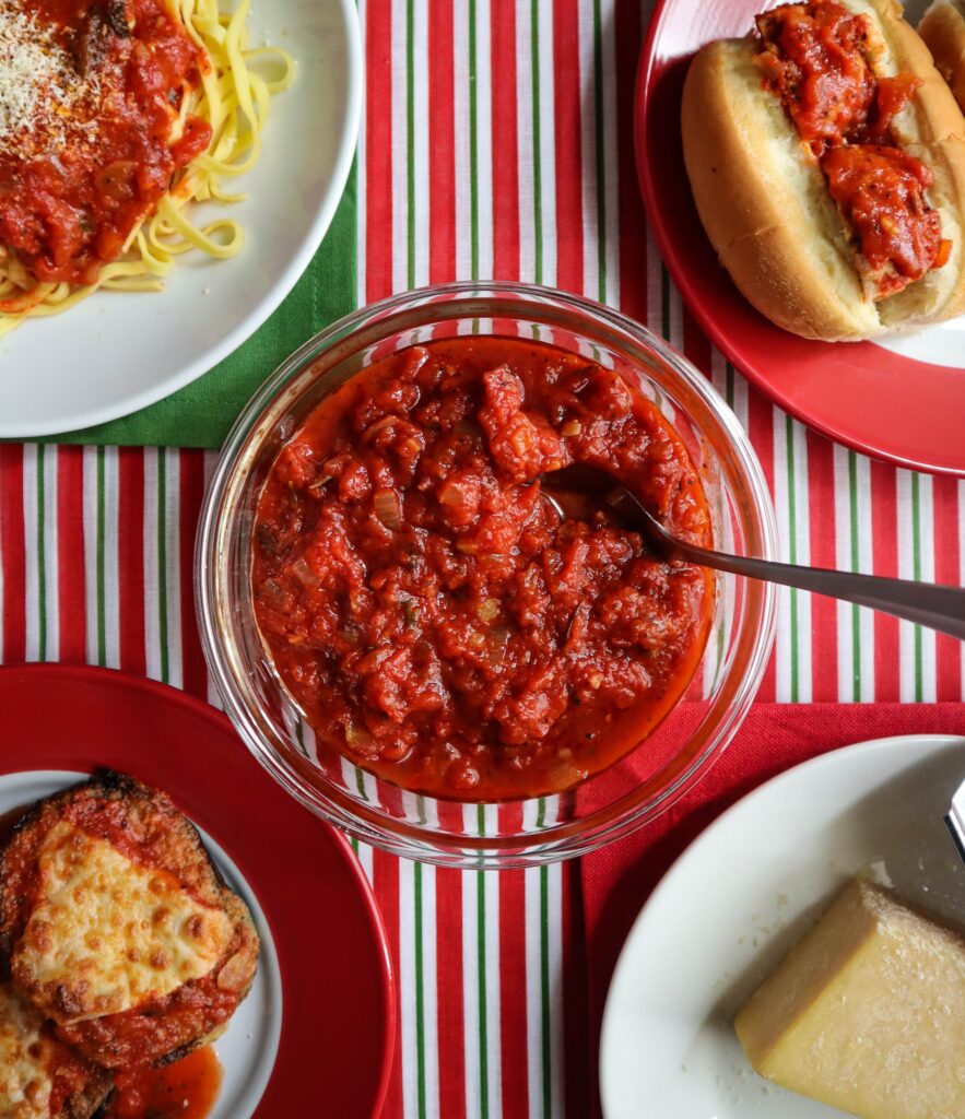 A bowl of homemade marinara sauce and a block of parmesan cheese used to make some meals made with it, spaghetti with sauce meatball subs eggplant parmesan