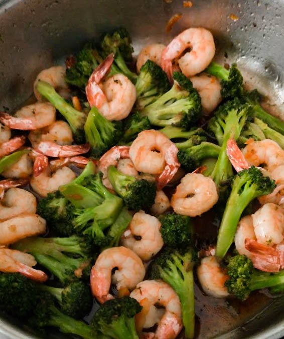 homemade orange sauce added to cooked shrimp and broccoli in skillet