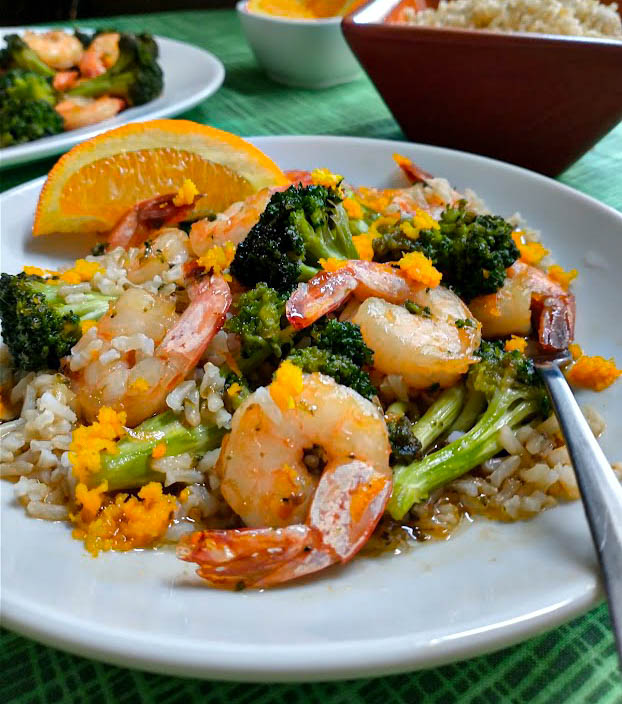 shrimp & broccoli with orange sauce served over brown rice with orange zest and a wedge of orange. 