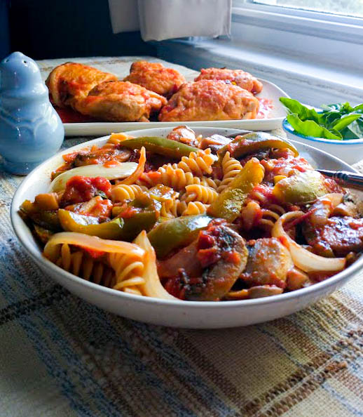 bowl of pasta smothered in a vegetable sauce served with breaded fried chicken thighs