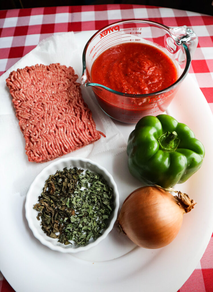 ingredients for american chop suey ground meat crushed tomato green pepper onion basil and oregano