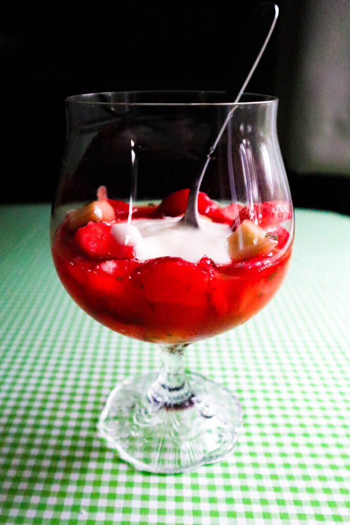 strawberry salad swimming in fresh strawberry juice with honey and a yogurt topping in a stemware glass 