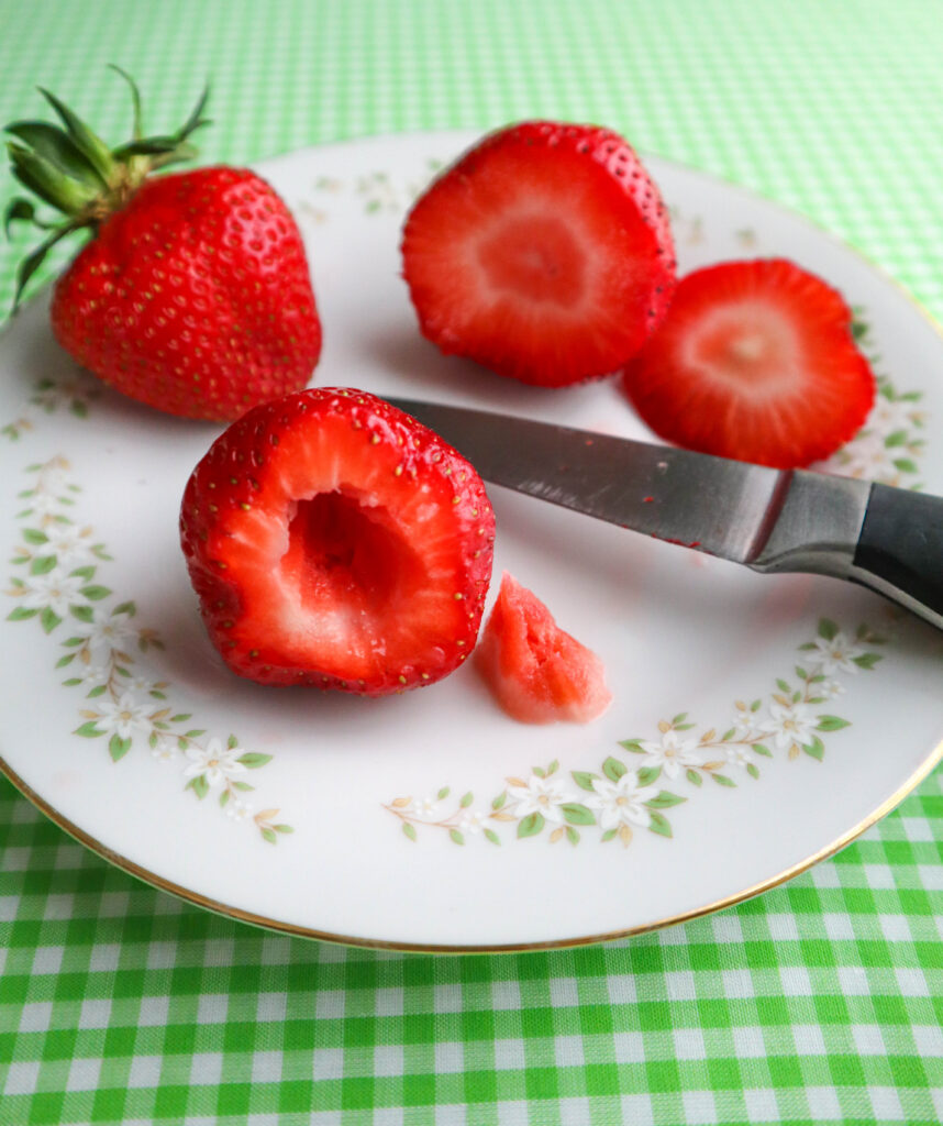 3 strawberries one whole one with top cut off one hulled 