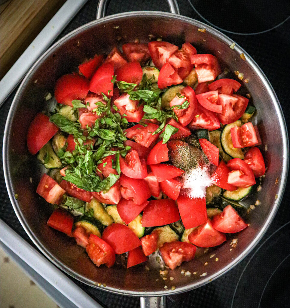 tomatoes torn basil leaves salt and pepper added to zucchini