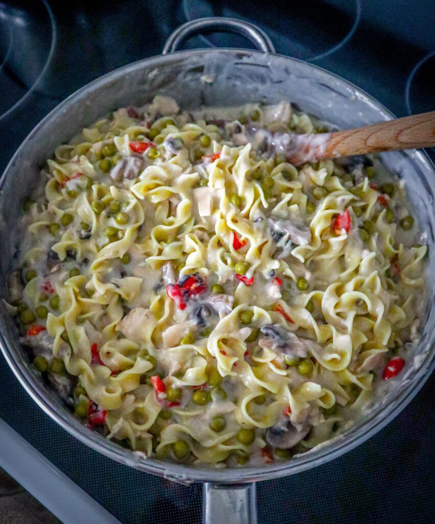 mixing the noodles into the other ingredients in the skillet