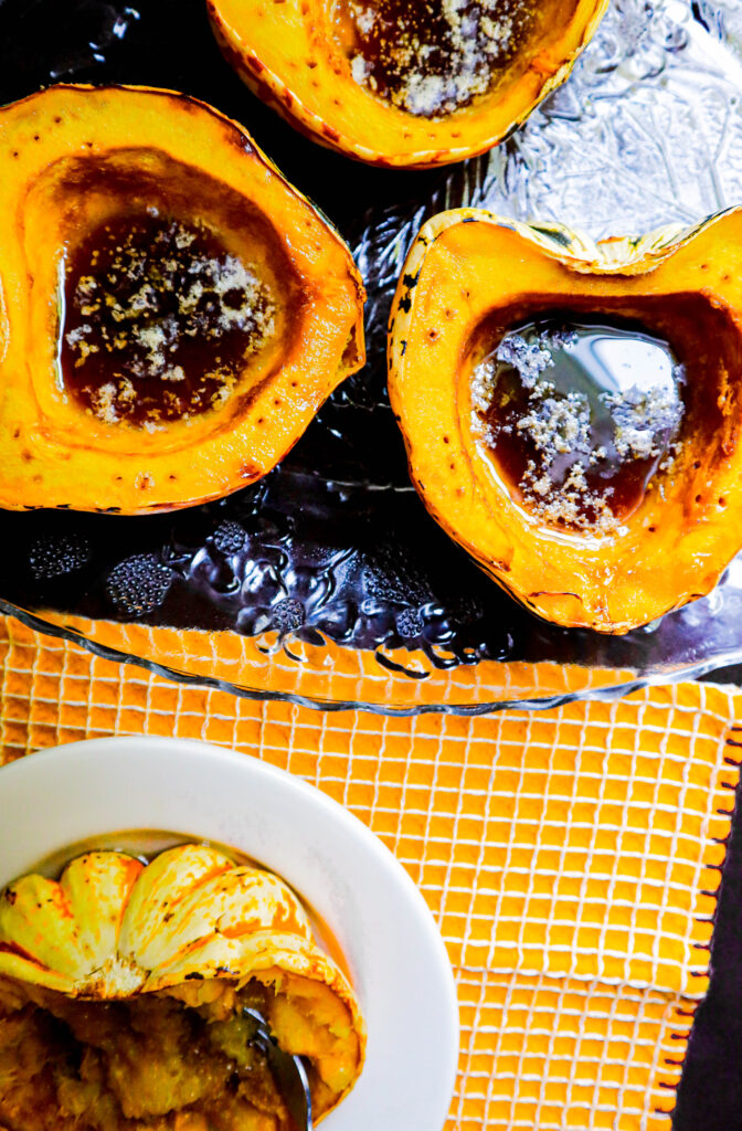 baked squash with melted butter and maple syrup in the well of the squash three halves on a platter and one half in a dish