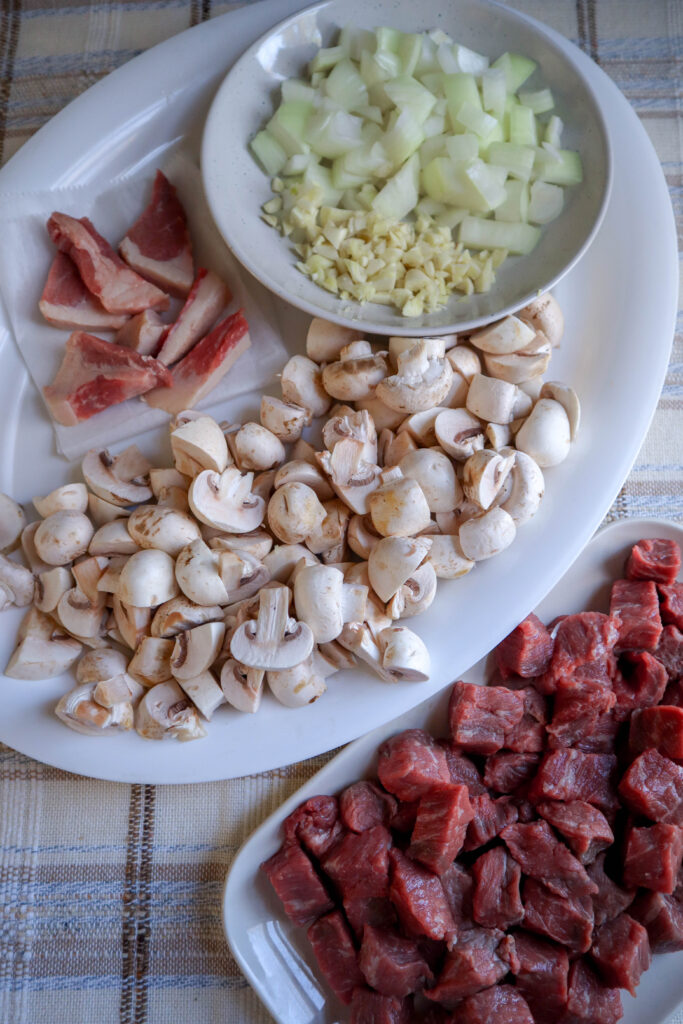 chopped onion garlic mushrooms cubes of beef and sliced beef fat prepared to make beef and beans stew