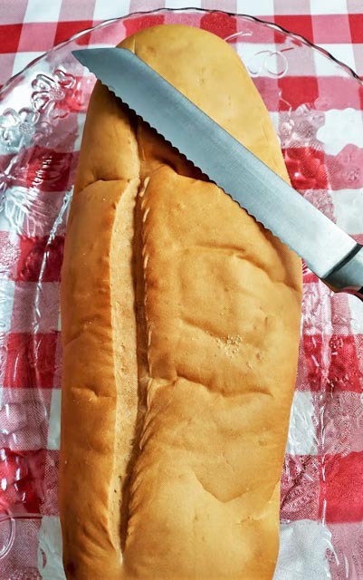 a loaf of italian bread with a serrated bread knife