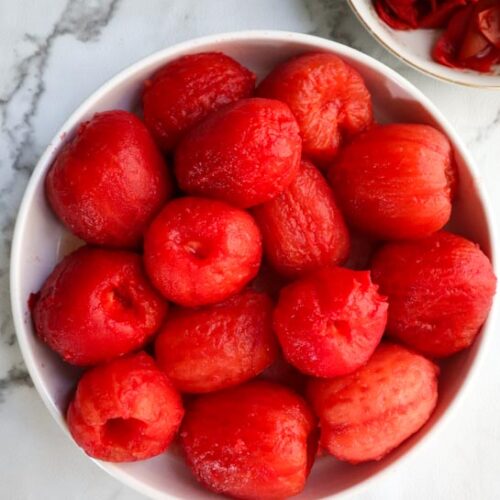 a white bowl plum tomatoes that have been peeled