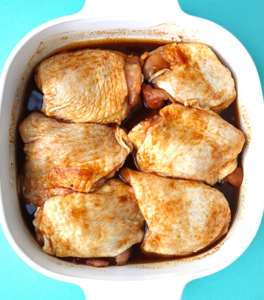 chicken thighs marinating in a baking dish