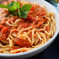 fresh tomato sauce over linguini served in a white bowl