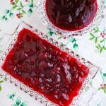 homemade whole berry and jellied cranberry sauce served in glass dishes on a white holiday tablecloth