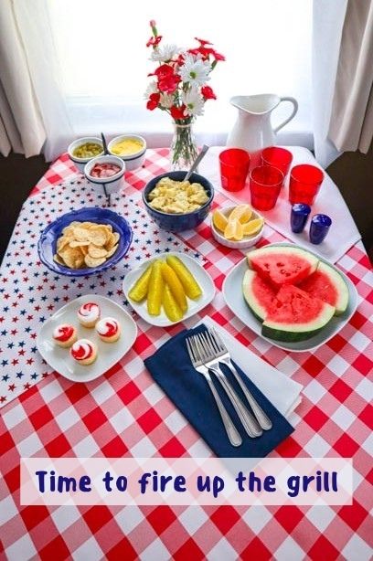 a summer table setting with a red and white gingham table cloth and blue and white dishes with summer side dishes